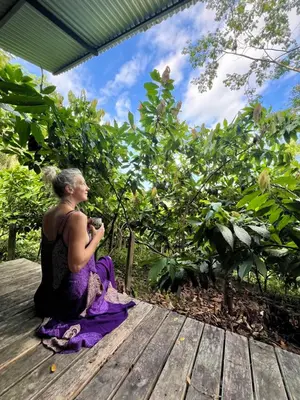 a woman sitting on a wooden deck taking a picture at The Emerald Haven in Parrita