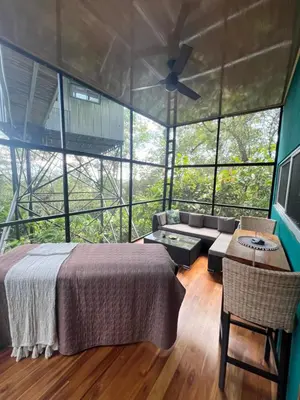 a bedroom with a bed and a couch in a room with windows at The Emerald Haven in Parrita