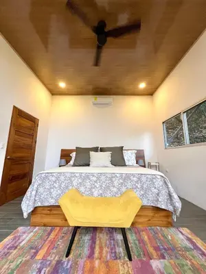 a bedroom with a large bed with a yellow bench at The Emerald Haven in Parrita