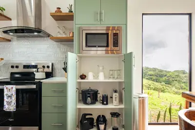 a kitchen with green cabinets and a microwave at Apricus Costa Rica in Monteverde Costa Rica