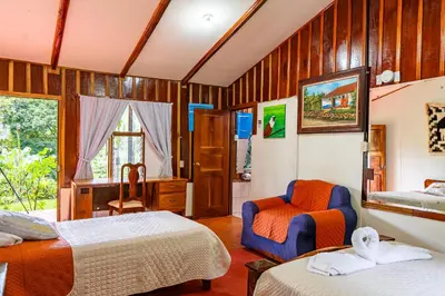 a room with two beds and a chair in it at Monteverde Wildlife Paradise - Nature Lovers in San Luis