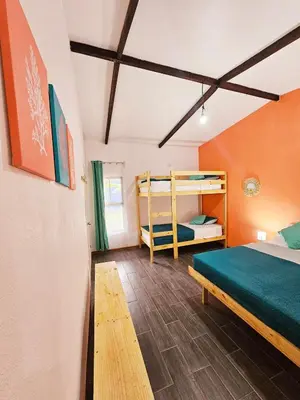 a room with a bed and bunk beds in it at Cara Coral, un oasis en la Selva in Tortuguero