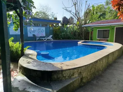 a swimming pool with a stone wall around it at Cara Coral, un oasis en la Selva in Tortuguero