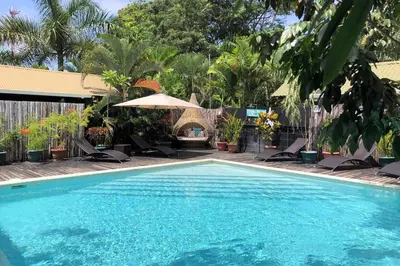 a swimming pool with chairs and an umbrella at Danyasa Eco-Retreat in Dominical