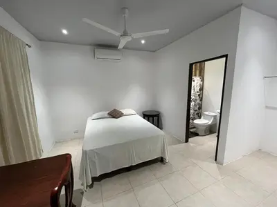 a white bedroom with a bed and a mirror at Casa playa 2 in Huacas