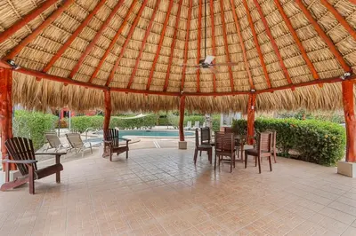 a pavilion with a table and chairs and a straw umbrella at VBM6 Delightful Beachside Cottage Close to Beach in Tamarindo