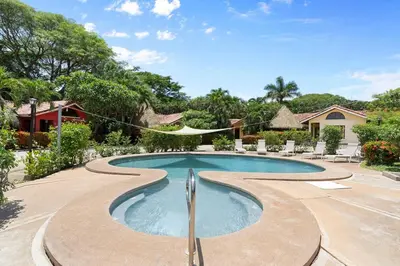 a swimming pool in a yard with chairs and a house at VBM6 Delightful Beachside Cottage Close to Beach in Tamarindo