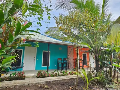 a small blue and orange house in a garden at Casa Selvamar, un oasis en la selva in Tortuguero