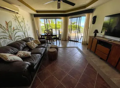 a living room with a leather couch and a flat screen tv at Beachfront Exotic Family Groups Retreat Wedding in Jacó
