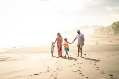 a family standing on the beach with footprints in the sand at Beachfront Exotic Family Groups Retreat Wedding in Jacó