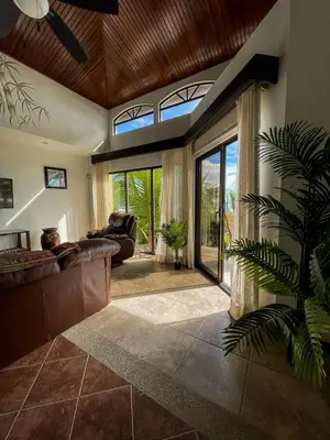 a living room with a couch and a large window at Beachfront Exotic Family Groups Retreat Wedding in Jacó
