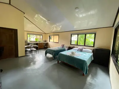 a room with two beds and a table in it at Estudio Jaguar 2 o piso Casa Jaguar in Tortuguero