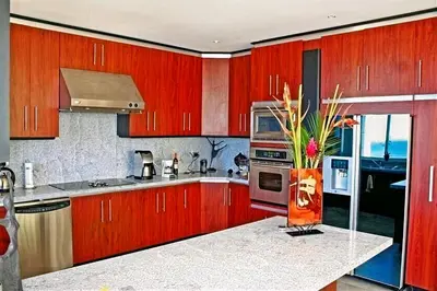 a kitchen with red cabinets and a vase of flowers on a counter at Modern 4 Bedroom Infinity Pool Beach, Sunset, in Playa Hermosa