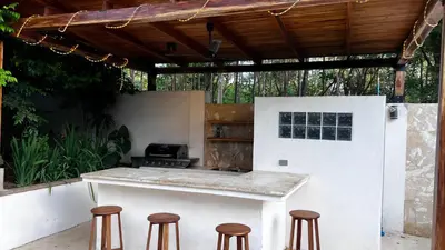 an outdoor kitchen with stools and a counter with a stove at Casa Veranera in Playa Grande