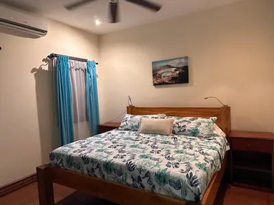 a bedroom with a bed and blue curtains at Casa Veranera in Playa Grande