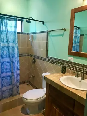 a bathroom with a toilet and a sink and a mirror at Casa Veranera in Playa Grande