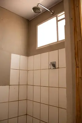 a bathroom with a window and white tiles at Noni Garden in Tamarindo