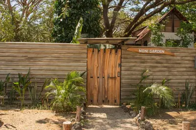 a wooden gate with a sign that reads main garden at Noni Garden in Tamarindo