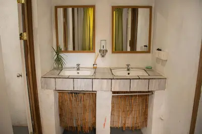 a bathroom with two sinks and two mirrors at Noni Garden in Tamarindo