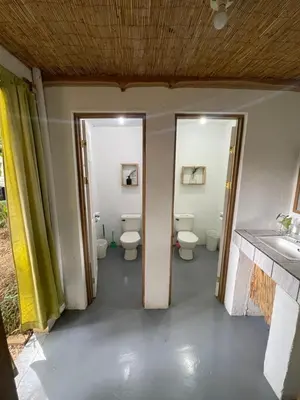 a bathroom with three toilets and a sink and two doors at Noni Garden in Tamarindo