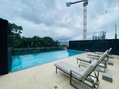 a swimming pool with lounge chairs on top of a building at Premium Apartment In Be Cariari in Heredia