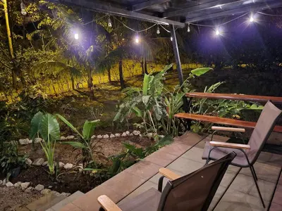 a patio with a wooden bench and chairs at night at El Congo Apartmento in Nicoya