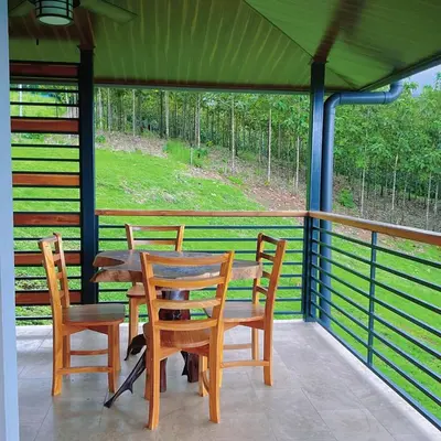 a table and chairs on a porch with a cat sitting on it at Casa Brisa house in the mountains 15 minutes from the beach in Nicoya