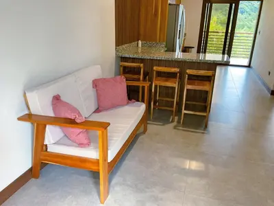 a living room with a white couch and a kitchen at Casa Brisa house in the mountains 15 minutes from the beach in Nicoya