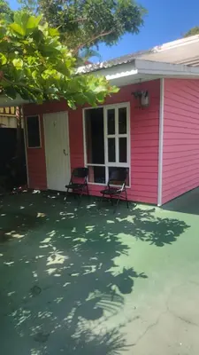 a pink house with two chairs in front of it at Residencial Oasis in Sámara