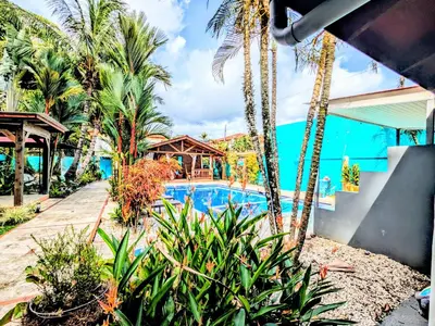 a resort swimming pool with palm trees and a house at Intimate Earthy Vibe - Bedroom in a Tropical Paradise in Herradura