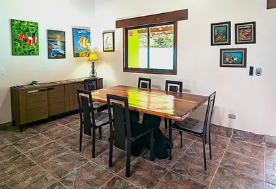a dining room with a wooden table and chairs at Lovely Tropical Ensuite Bedroom - Pool AC Hot Water in Herradura