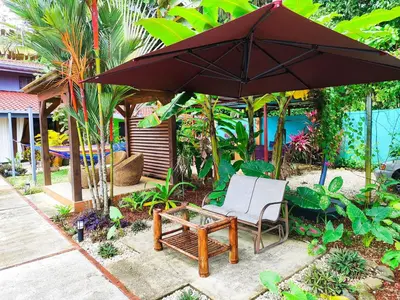 an umbrella and a chair and a table and a bench at Lovely Tropical Ensuite Bedroom - Pool AC Hot Water in Herradura