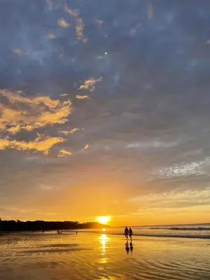 two people walking on the beach at sunset at Studio apartment on the beach in Tamarindo