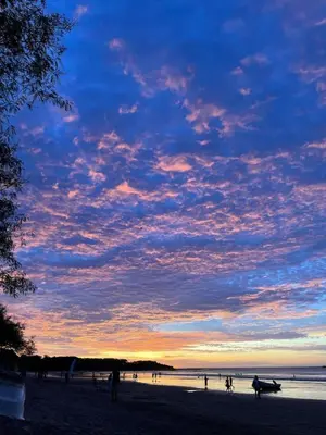 a group of people on a beach at sunset at Studio apartment on the beach in Tamarindo