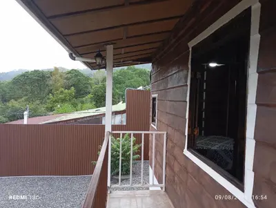 a balcony of a house with an open door at Cabaña Renaciendo in Turrialba
