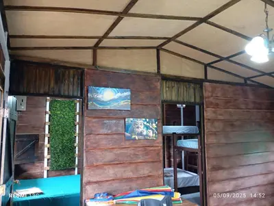 a room with a wooden wall and a room with a table at Cabaña Renaciendo in Turrialba