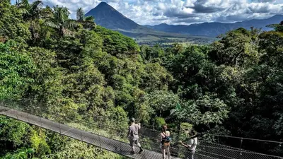 three people on a suspension bridge in the forest at La Fortuna, Fluca House 3 in Fortuna