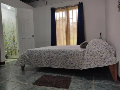 a bedroom with a bed with a comforter and a window at Hostel Cora Chia in Pedregal