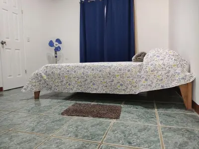 a couch in a room with a blue curtain at Hostel Cora Chia in Pedregal