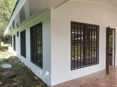 a side view of a white building with black gates at Hostel Cora Chia in Pedregal