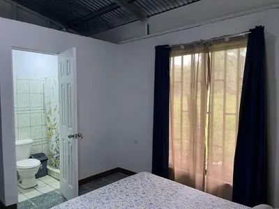 a bedroom with a bed and a bathroom with a toilet at Hostel Cora Chia in Pedregal