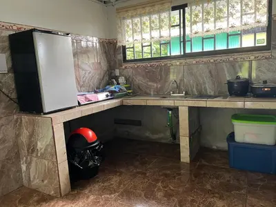 a kitchen with a counter and a sink and windows at Hostel Cora Chia in Pedregal