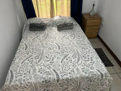 a bed with a white comforter with two bags on it at Hostel Cora Chia in Pedregal