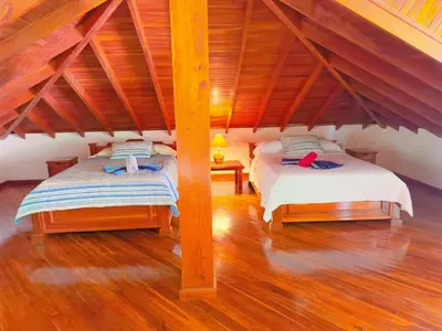 two beds in a room with wooden floors at Casa Mariposa cozy house 5 minutes from the beach in Sámara