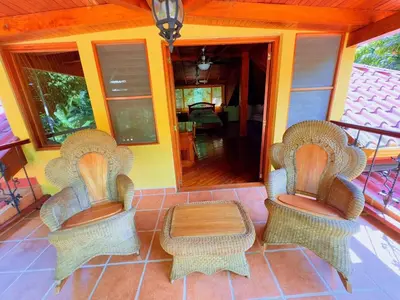 three wicker chairs and a table on a porch at Casa Mariposa cozy house 5 minutes from the beach in Sámara
