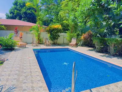 a swimming pool in a yard with chairs and trees at Casa Mariposa cozy house 5 minutes from the beach in Sámara