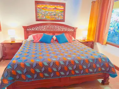a bedroom with a bed with a colorful comforter at Casa Mariposa cozy house 5 minutes from the beach in Sámara
