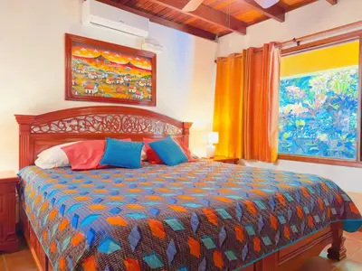 a bedroom with a large bed with colorful pillows at Casa Mariposa cozy house 5 minutes from the beach in Sámara