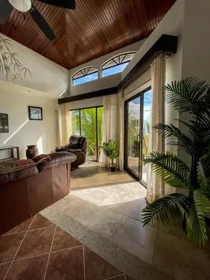 a living room with a couch and a large window at Beachfront Balcony Sunset 2B in Jacó