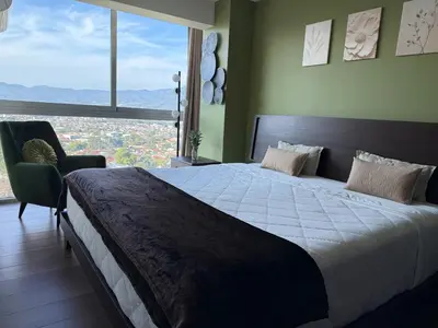 a bedroom with a large bed and a large window at Penthouse San José Costa Rica in San José